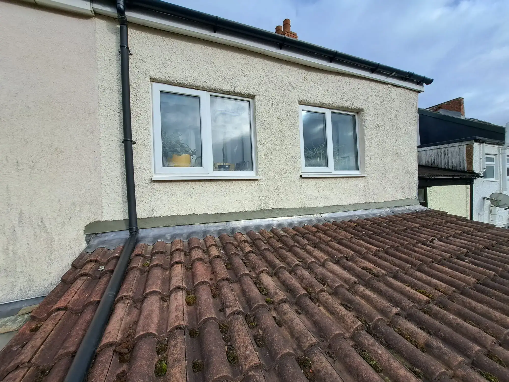 Tiled roof with flashing where it meets a rendered wall